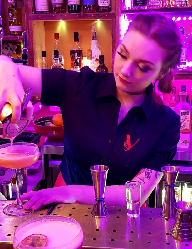 Young lady pouring cocktail embroidered blouse